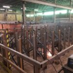 Welding activity and steel rack frames in a fabrication area. View 3 of 5