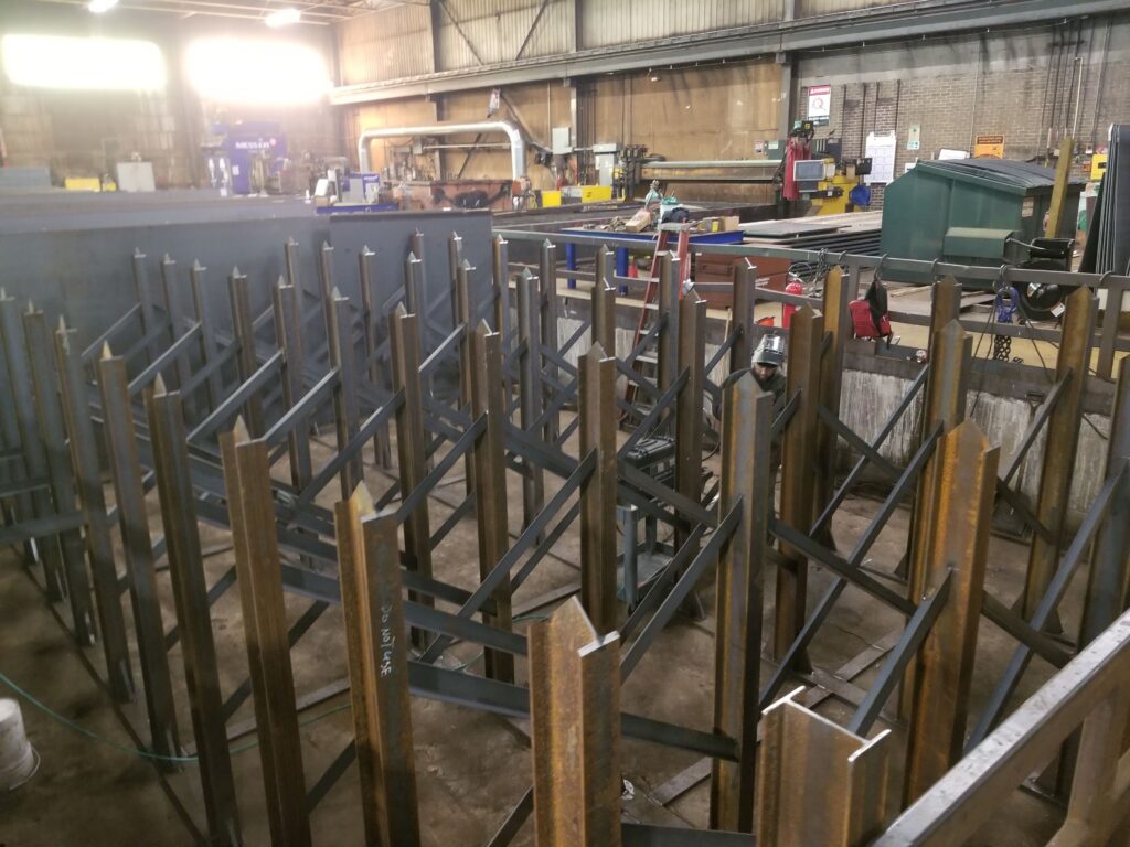 Welding activity and steel rack frames in a fabrication area. View 4 of 5