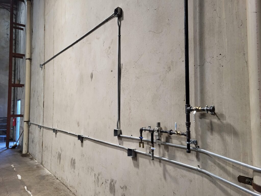 Installed plant-air piping running along an industrial wall