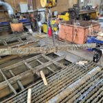 Old slat sections and accumulated material being removed from the cutting table