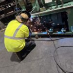 Worker welding on green industrial equipment