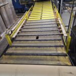 Multiple views along a sloped industrial conveyor with yellow side structure. View 2 of 4