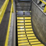 Multiple views along a sloped industrial conveyor with yellow side structure. View 3 of 4