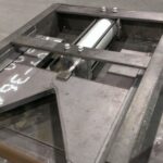 Raw steel frame and fitted components on a work surface